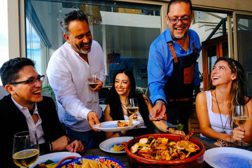 Cheerful mature men with children enjoying dinner at home