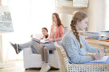 Three teenage girls doing homework in room
