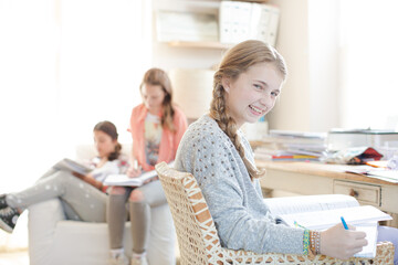 Three teenage girls doing homework in room