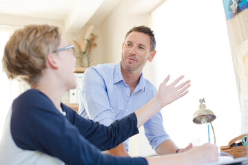 Obraz premium Father helping teenage son doing his homework in room