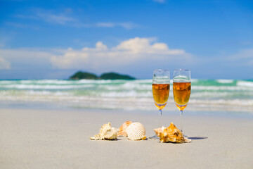 Two glasses of champagne on sand beach with shell