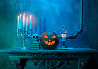 Scary laughing pumpkin and old skull on ancient gothic fireplace. Halloween, witchcraft and magic.