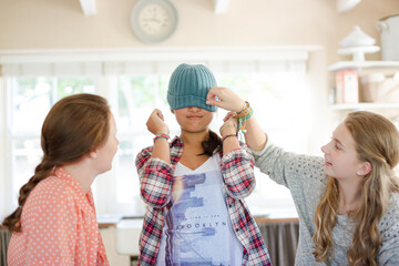 Three teenage girls playing with beanie in dining room