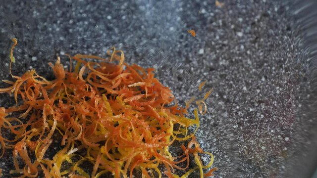 Gruepfruit peel falls into a transparent bowl. Peeling citrus orange fruit to make lemonade