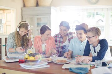 Group of smiling teenagers gathered around table in dining room