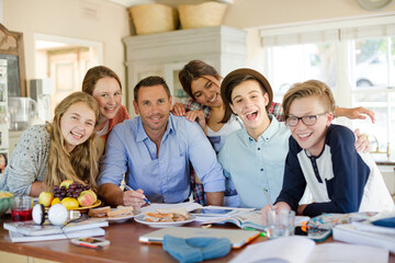 Group of teenagers with mid adult man sitting at table in dining room