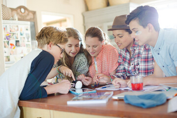 Group of teenagers using together digital tablet at table in kitchen