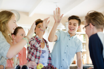 Group of teenagers doing high five in living room