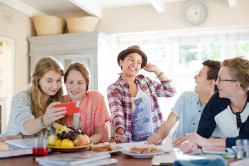 Group of smiling teenagers gathered around table in dining room