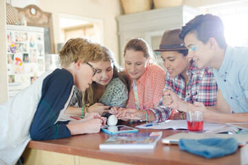 Fototapeta premium Group of teenagers using together digital tablet at table in kitchen