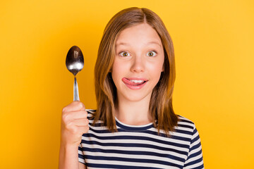 Photo of funny cheerful person arm hod spoon tongue out lick lip isolated on yellow color background - obrazy, fototapety, plakaty