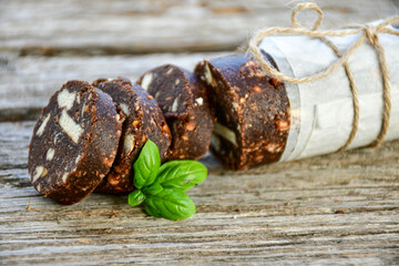 Homemade delicious  traditional Italian dessert Chocolate salami cake  with walnuts and biscuits on  wooden ackground. 