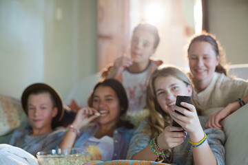 Group of teenagers having fun while watching tv on sofa