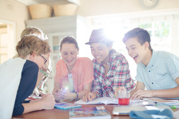 Fototapeta premium Group of teenagers using together digital tablet at table in kitchen