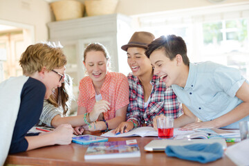 Group of teenagers using together digital tablet at table in kitchen