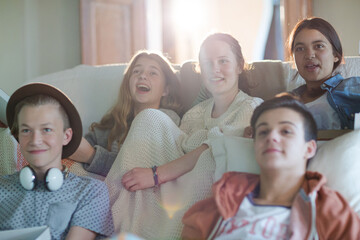 Group of teenagers watching tv on sofa together