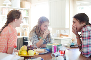 Teenage girls learning at table in kitchen