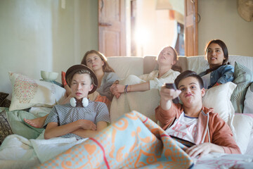 Group of teenagers watching tv on sofa together