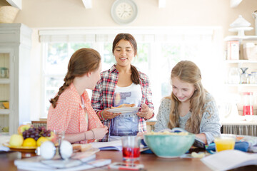 Teenage girls learning at table in kitchen