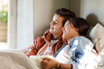 Teenage couple lying in bed and watching tv