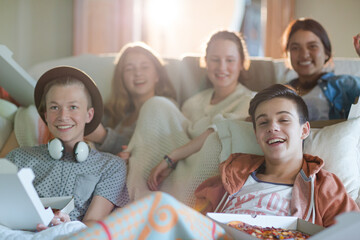 Group of teenagers watching tv on sofa together