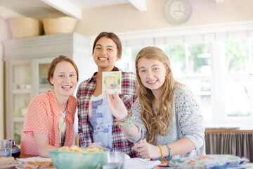 Three teenage girls looking at photograph while sitting at table