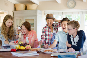 Fototapeta premium Group of smiling teenagers gathered around table in dining room