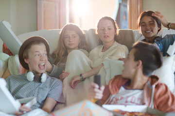 Group of teenagers watching tv on sofa together