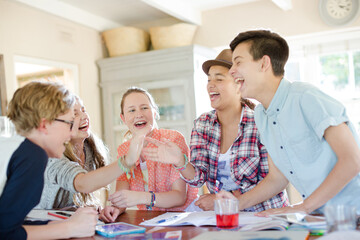 Group of teenagers using together digital tablet at table in kitchen