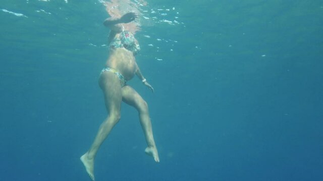 Donna incinta nuota nel mare durante la gravidanza