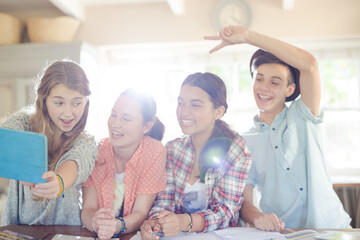 Group of smiling teenagers taking selfie in dining room