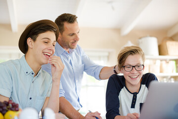Fototapeta premium Teenage boys with father using laptop in dining room