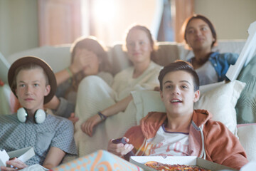 Group of teenagers watching tv on sofa together