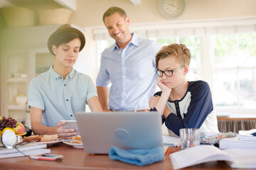 Obraz premium Teenage boys with father using laptop in dining room