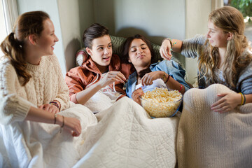 Fototapeta na wymiar Group of teenagers throwing popcorn on themselves on sofa