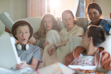 Group of teenagers watching tv on sofa together
