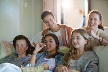 Group of teenagers having fun while watching tv on sofa