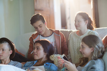 Group of teenagers having fun while watching tv on sofa