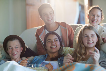 Group of teenagers having fun while watching tv on sofa