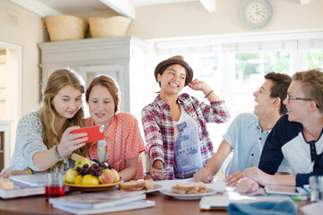 Group of smiling teenagers gathered around table in dining room