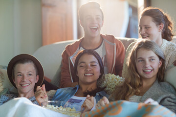 Group of teenagers having fun while watching tv on sofa