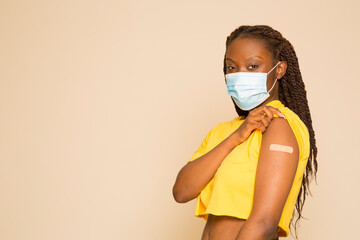 Studio portrait of woman with face mask and adhesive bandage after vaccination