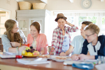 Group of smiling teenagers gathered around table in dining room