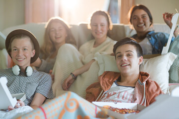 Group of teenagers watching tv on sofa together