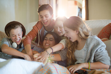 Group of teenagers throwing popcorn on themselves while sitting on sofa