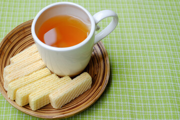 wafers on plaid tablecloth with a white cup of tea