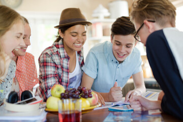 Group of teenagers using together digital tablet at table in kitchen