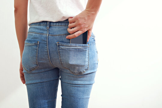 Woman takes out smartphone from her rear pocket of jeans 