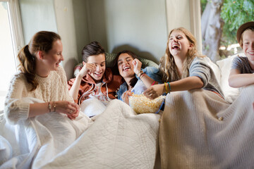 Group of teenagers throwing popcorn on themselves on sofa