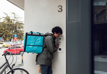 Male courier with bicycle delivering packages in city.